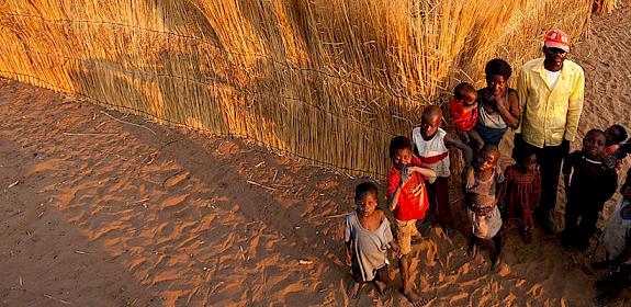 Community members standing in front of their home in the Zambezi Region