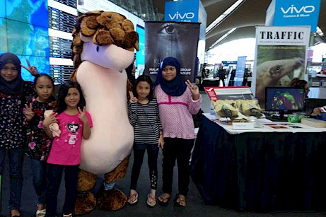 Passengers pose by Manis, TRAFFIC's pangolin mascot, at the roadshow after learning about how to remain vigilant for suspected wildlife trafficking